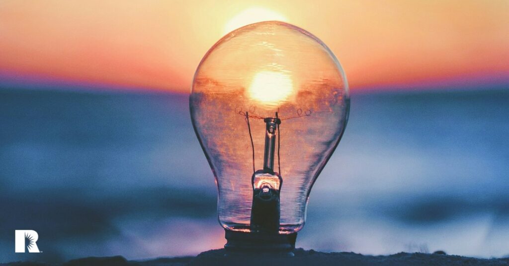 A photo of a lightbulb set against a sunset.