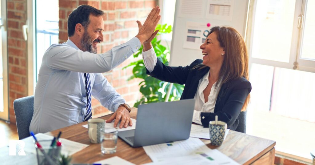 Two insurance agents share a high-five over their decision to join an agency network.