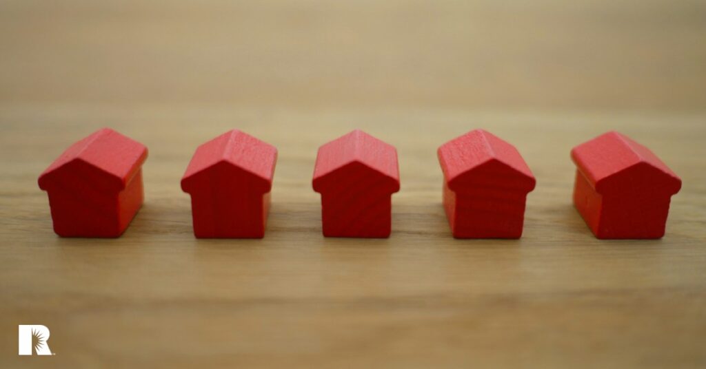 Several small wooden red houses illustrating strength in numbers.
