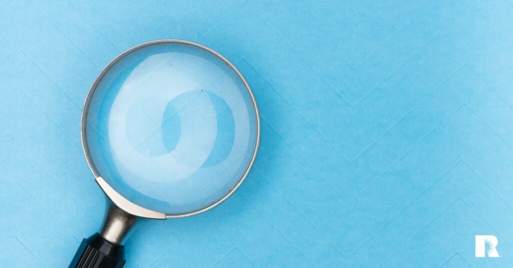 Photo illustration showing a magnifying glass against a blue background.